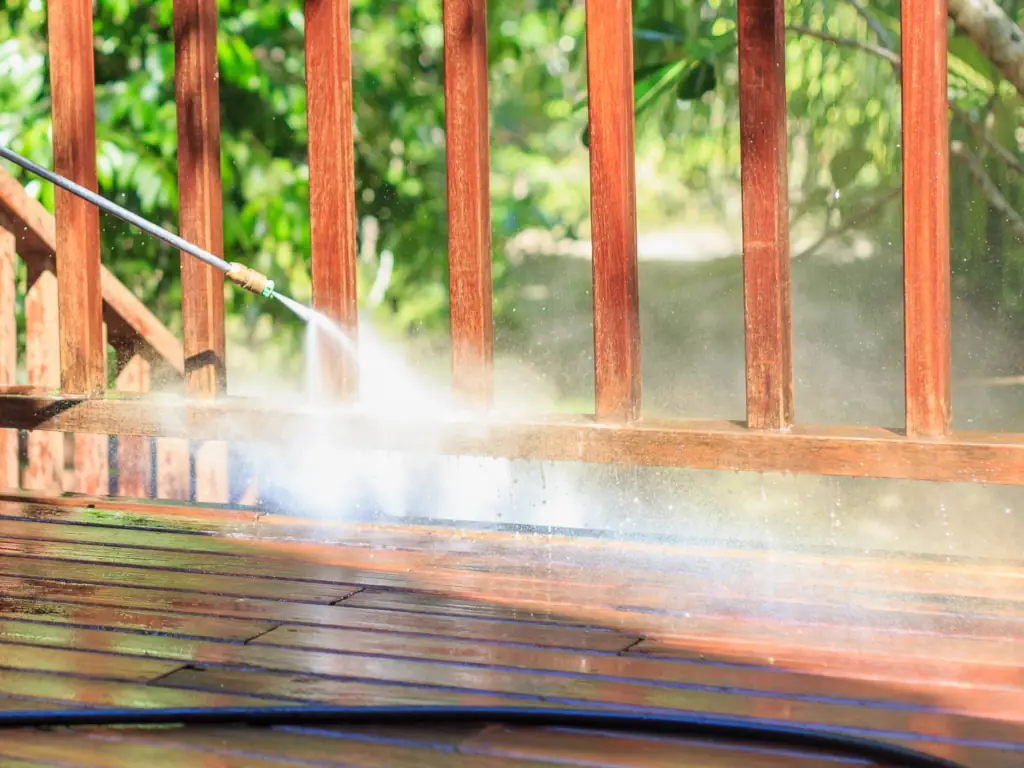 Pressure washing a wood deck railing and floor during an exterior property cleaning service in South Jersey.
