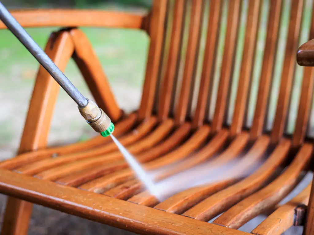 Pressure washer spray wand cleaning an outdoor wood chair in Collingswood, NJ — removing mold, mildew, and weathered grime from patio furniture and exterior wood surfaces.
